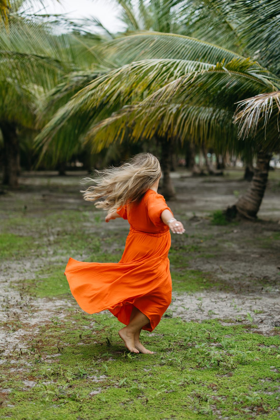 Mel twirling in an orange dress among the palm trees in the US Virgin Islands